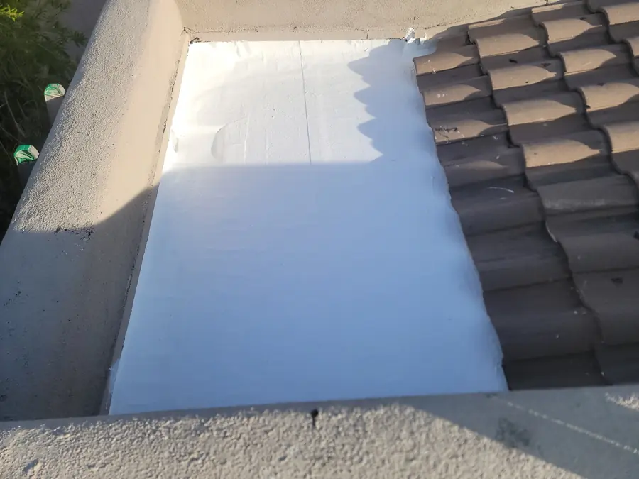White roof coating sealed where a flat roof meets concrete tile