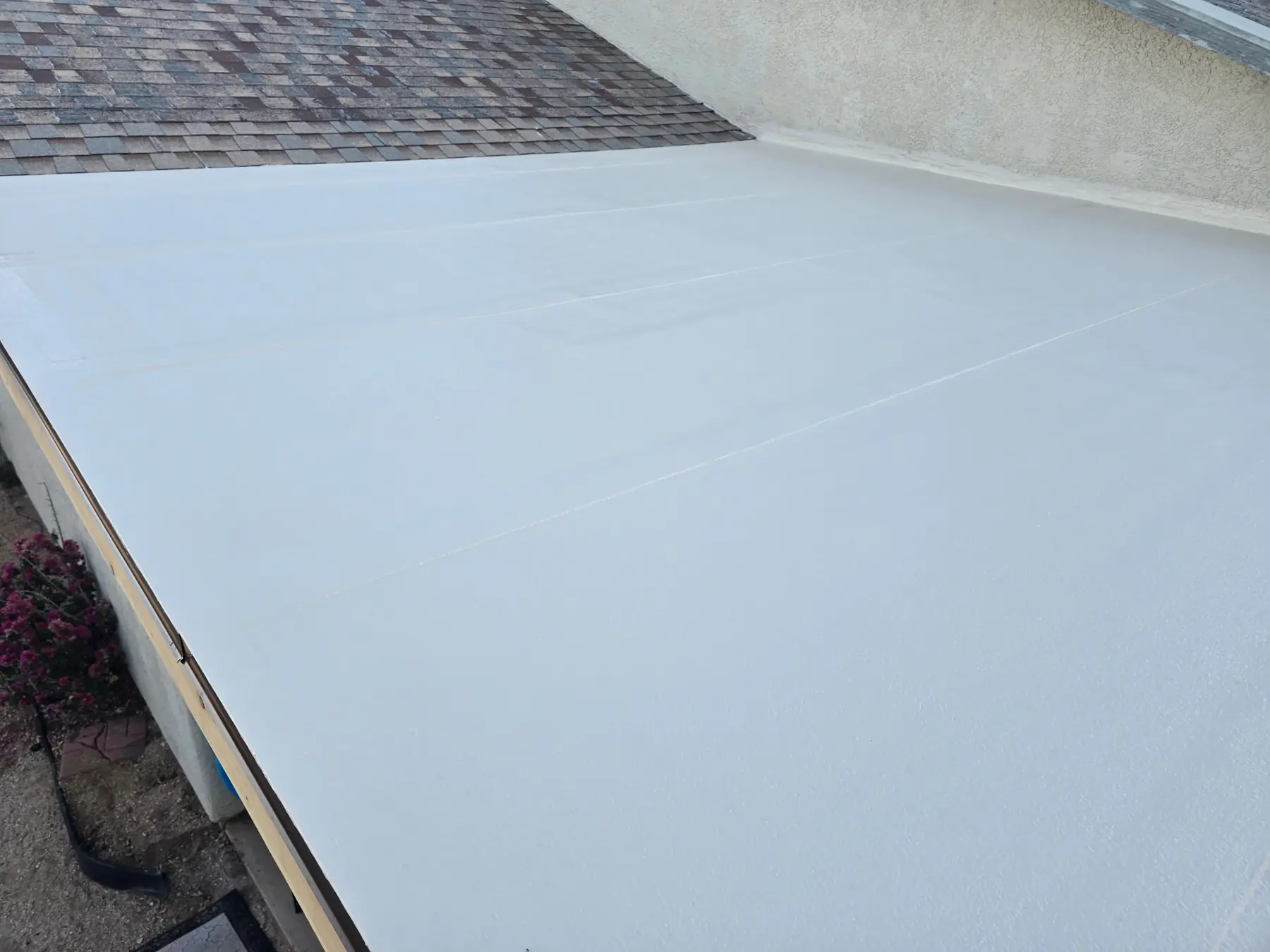 New white reflective coating at the transition between flat and shingle roofing